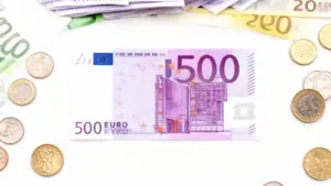 Banconota da 500 euro circondata da monete e altre banconote euro