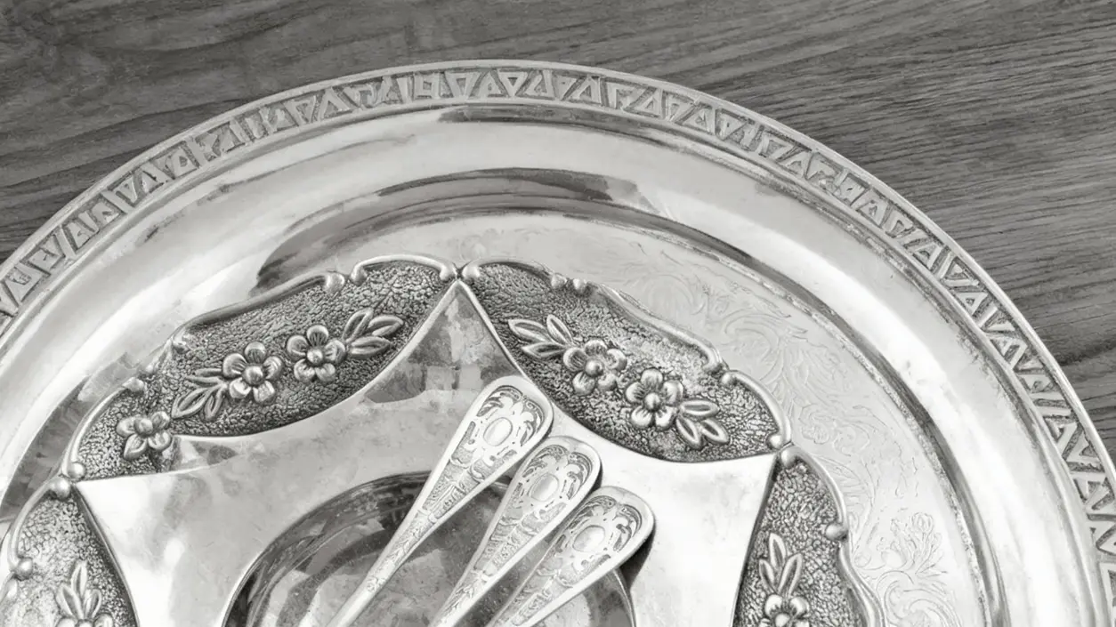 Dettaglio di un vassoio d'argento con cucchiaini decorativi su tavolo in legno