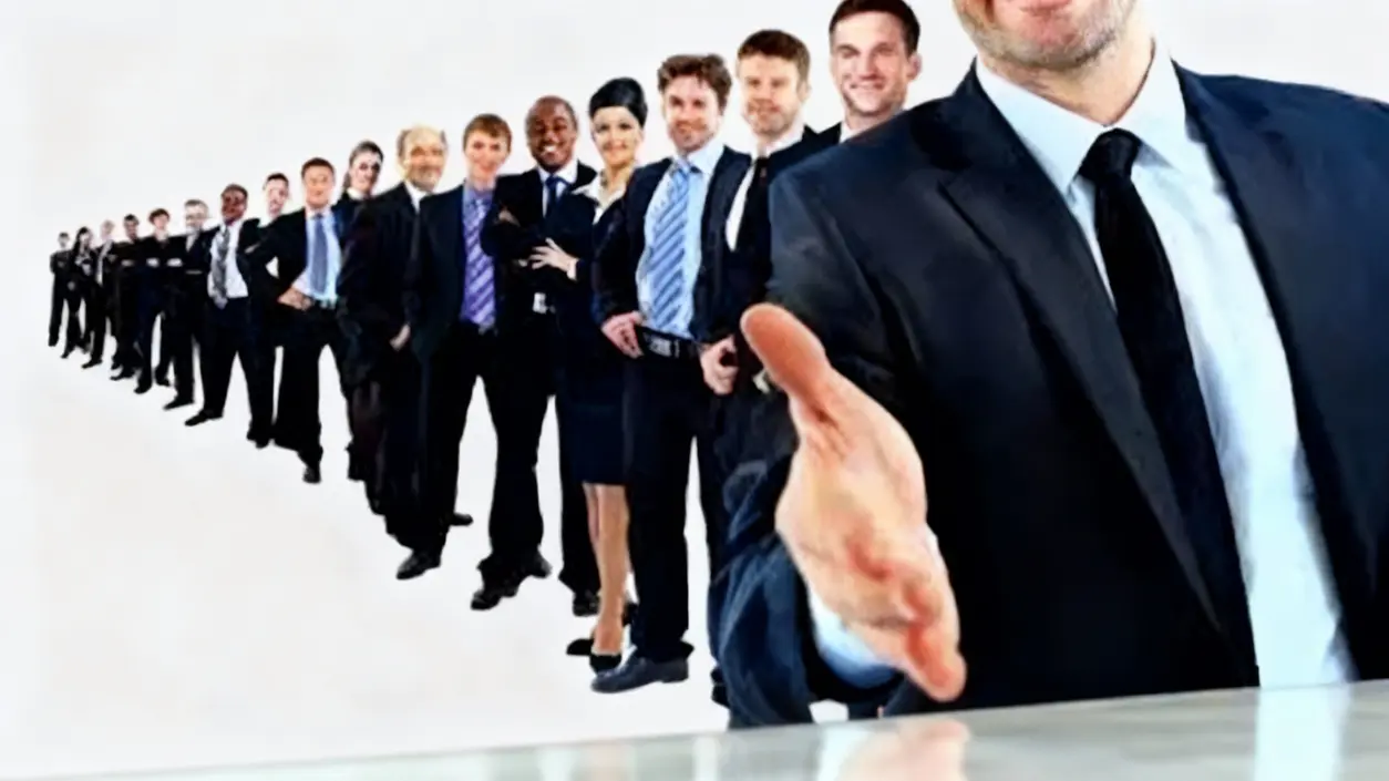 Persone in abbigliamento formale in fila, una in primo piano con mano tesa