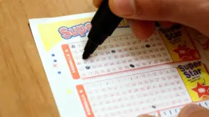 Una persona compila una schedina del SuperEnalotto con una penna nera